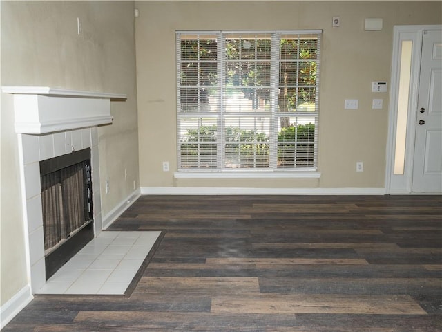 unfurnished living room featuring a fireplace, baseboards, and wood finished floors