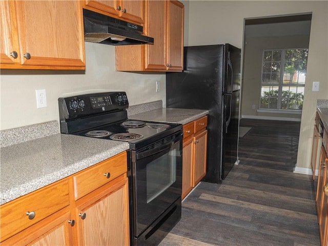 kitchen with brown cabinets, dark wood-type flooring, under cabinet range hood, light countertops, and black appliances