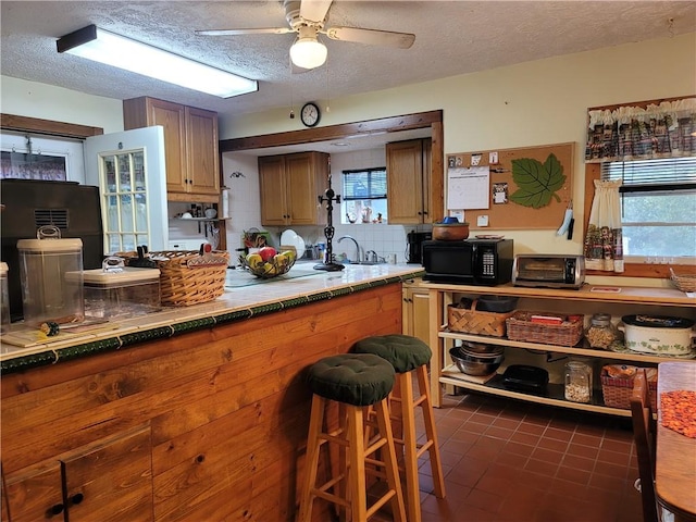 kitchen featuring tile countertops, ceiling fan, a textured ceiling, and a healthy amount of sunlight