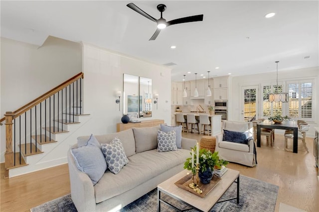 living room featuring ceiling fan with notable chandelier, sink, and light hardwood / wood-style floors