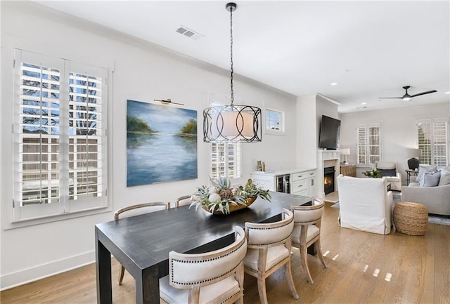 dining area with ceiling fan with notable chandelier and light hardwood / wood-style floors