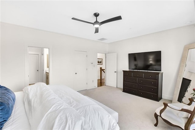 bedroom with ensuite bathroom, light carpet, and ceiling fan