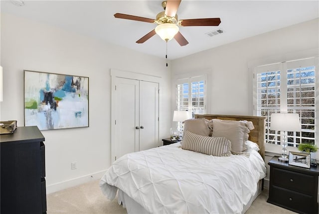 bedroom with light carpet, ceiling fan, and a closet