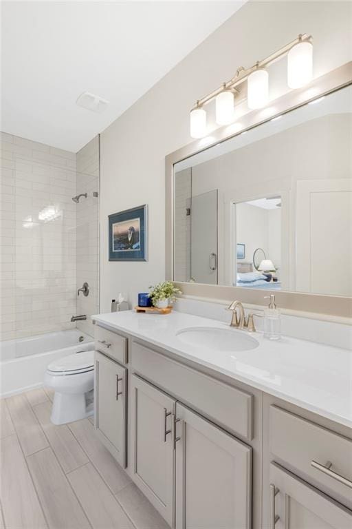 full bathroom featuring tiled shower / bath, vanity, and toilet