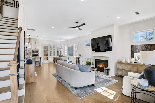 living room featuring wood-type flooring, ceiling fan, and a high end fireplace