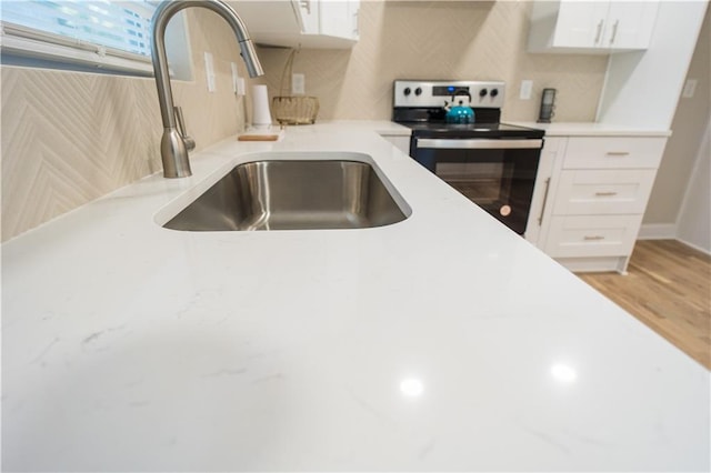 kitchen featuring backsplash, white cabinetry, sink, and stainless steel range with electric cooktop