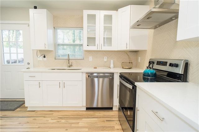 kitchen featuring sink, wall chimney exhaust hood, stainless steel appliances, backsplash, and white cabinets