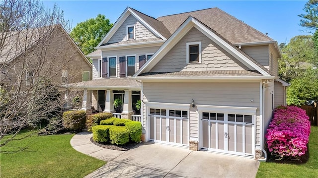 craftsman-style home featuring concrete driveway, a porch, roof with shingles, a front yard, and a garage