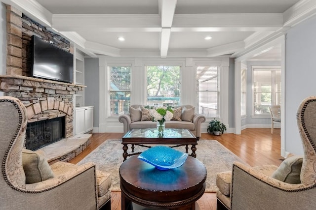 living area featuring beam ceiling, wood finished floors, a fireplace, and crown molding