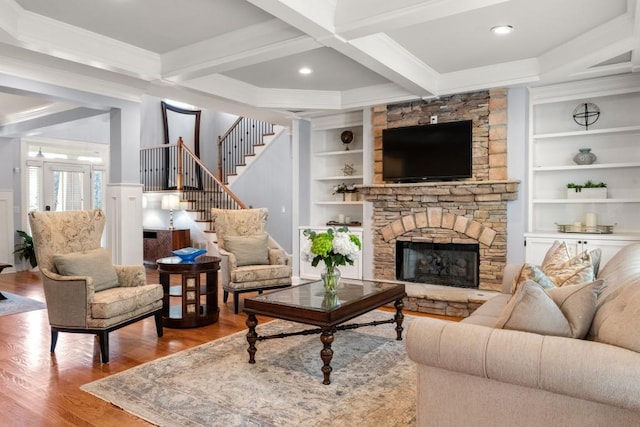 living room featuring wood finished floors, stairs, built in shelves, beamed ceiling, and ornamental molding