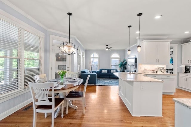 kitchen with white cabinets, visible vents, crown molding, and a sink