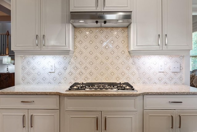 kitchen with stainless steel gas cooktop, white cabinets, tasteful backsplash, and ventilation hood