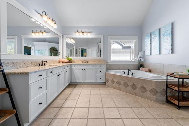 full bathroom with tile patterned flooring, double vanity, vaulted ceiling, a sink, and a garden tub