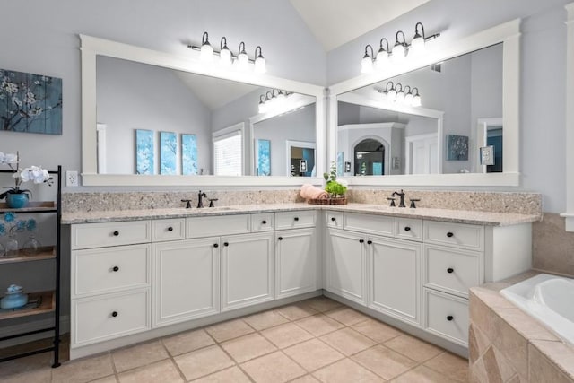 bathroom with double vanity, vaulted ceiling, tile patterned flooring, and a sink