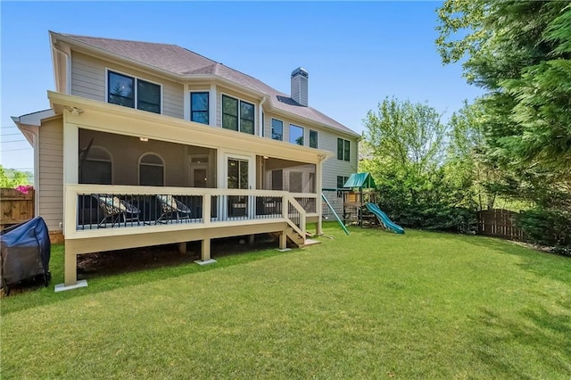 back of property featuring fence, a sunroom, a yard, and a playground