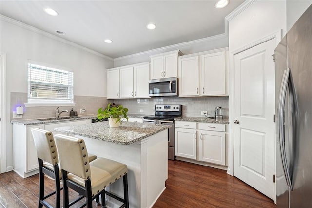 kitchen featuring appliances with stainless steel finishes, dark wood finished floors, white cabinets, and a sink