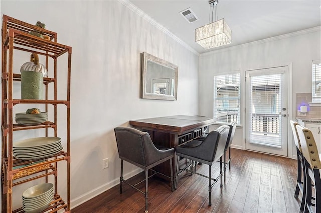 dining room featuring dark wood finished floors, crown molding, visible vents, a chandelier, and baseboards