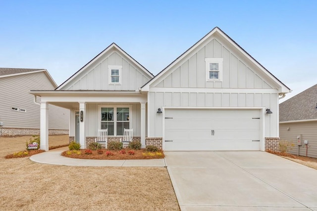 view of front of property featuring a porch, an attached garage, brick siding, concrete driveway, and board and batten siding