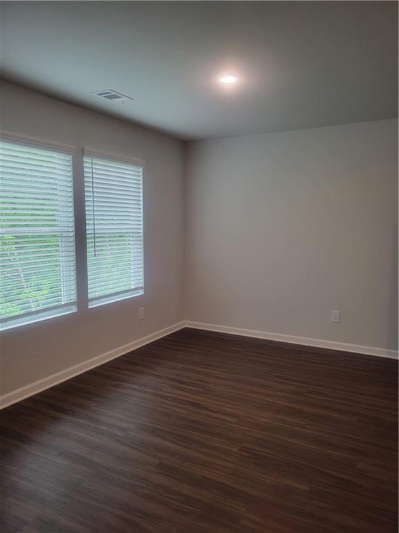 unfurnished room with recessed lighting, baseboards, dark wood finished floors, and visible vents
