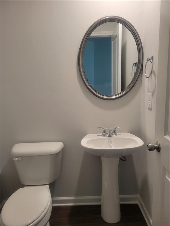 bathroom with baseboards, toilet, and wood finished floors