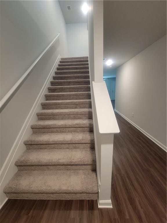 stairway featuring baseboards, wood finished floors, and visible vents