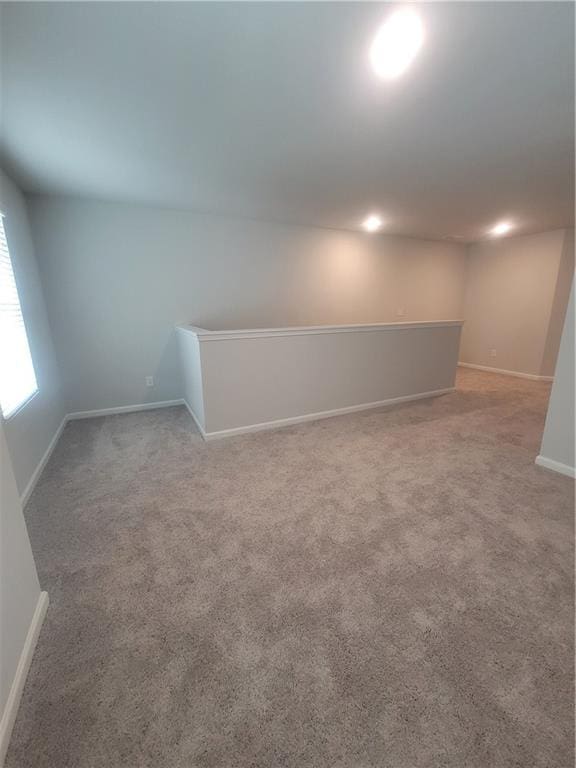 spare room with baseboards and light carpet