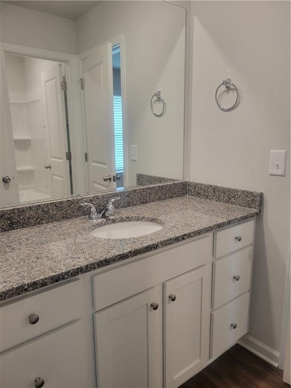 bathroom with vanity, baseboards, and wood finished floors