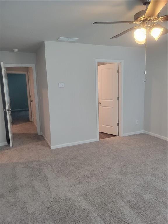 carpeted empty room featuring baseboards, ceiling fan, and visible vents