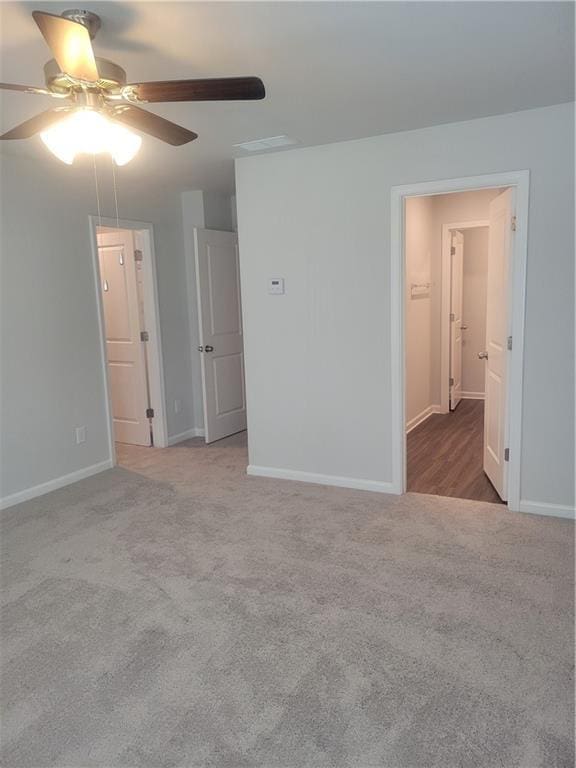 carpeted spare room featuring ceiling fan and baseboards