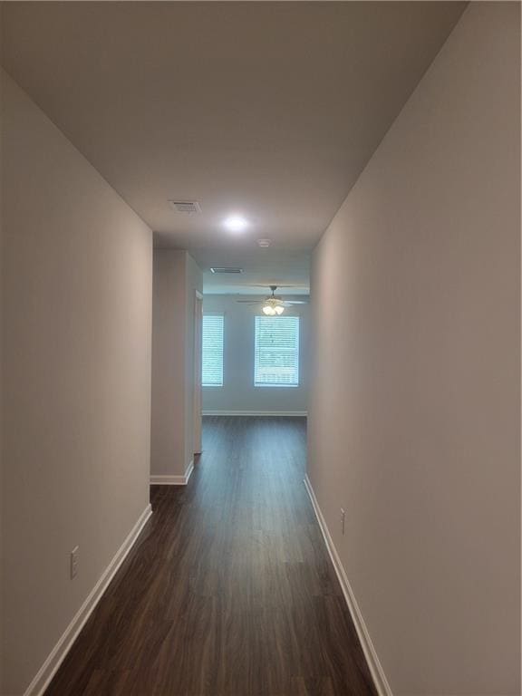hallway featuring baseboards, dark wood finished floors, and visible vents