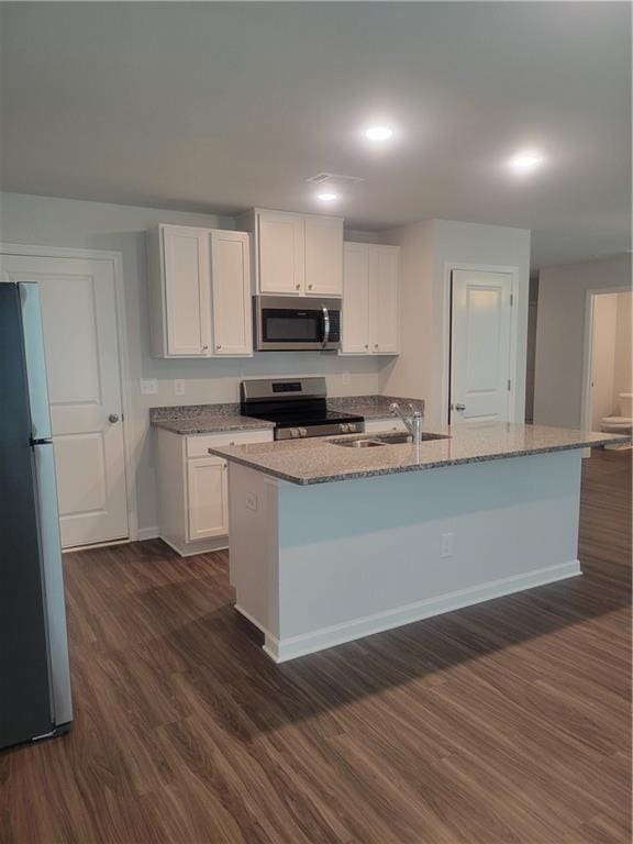 kitchen with appliances with stainless steel finishes, light stone countertops, a sink, dark wood-style floors, and white cabinetry