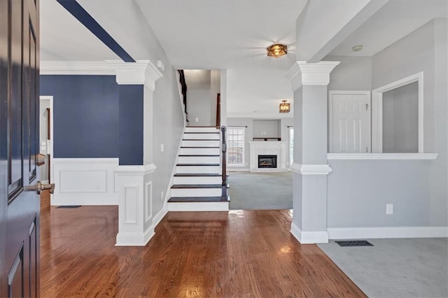 foyer entrance with dark hardwood / wood-style floors, ornamental molding, and decorative columns