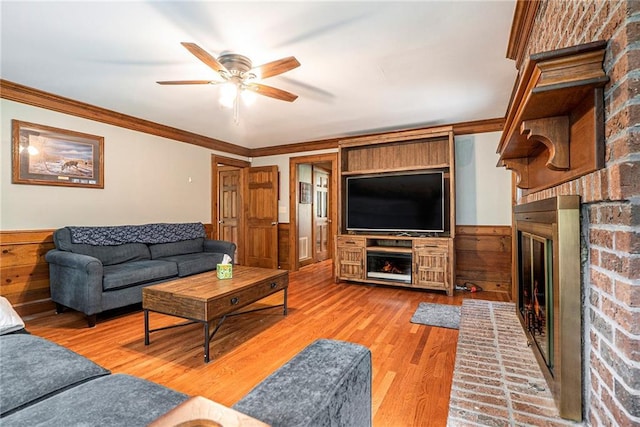 3392 Inns Brook Way, Snellville, GA 30039 - living room featuring a brick fireplace, ceiling fan, wood finished floors, wainscoting, and crown molding