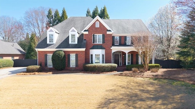 view of front of home with brick siding, covered porch, and a front yard