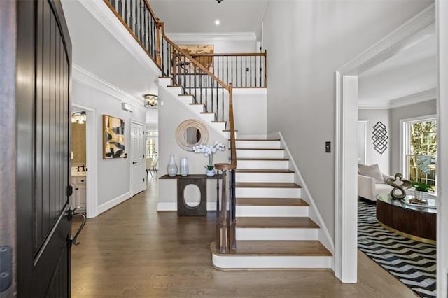 foyer with baseboards, dark wood finished floors, stairs, ornamental molding, and a towering ceiling