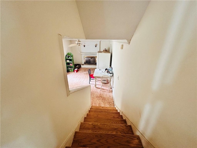stairway featuring a glass covered fireplace and lofted ceiling