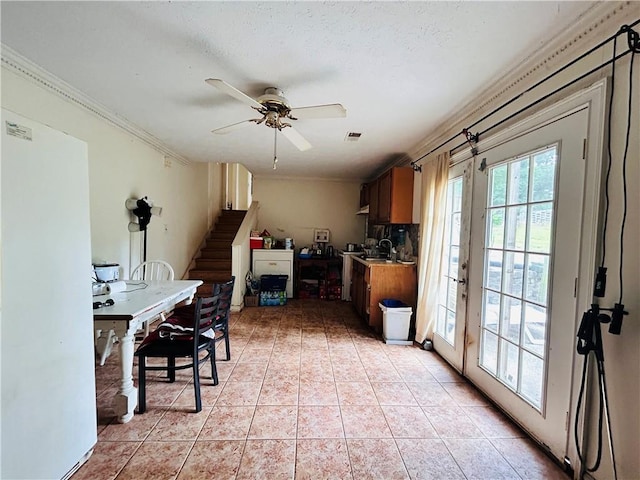 kitchen featuring ornamental molding, a ceiling fan, light tile patterned floors, tasteful backsplash, and light countertops