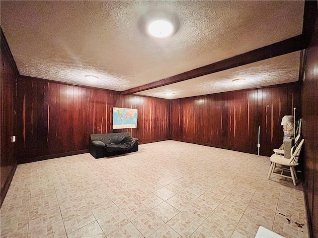 finished below grade area with a textured ceiling, wooden walls, and tile patterned flooring