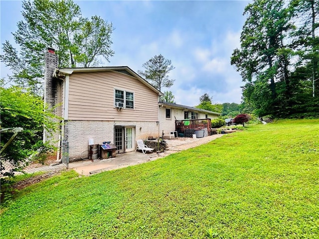 back of house with a chimney, a patio area, a lawn, a deck, and brick siding