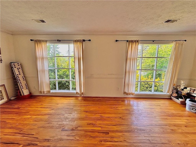 unfurnished room featuring wood finished floors, a textured ceiling, and ornamental molding
