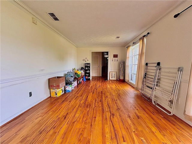 living area featuring light wood finished floors, crown molding, and baseboards