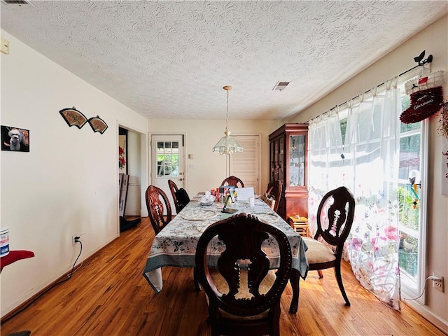 dining space featuring wood finished floors, a textured ceiling, and baseboards