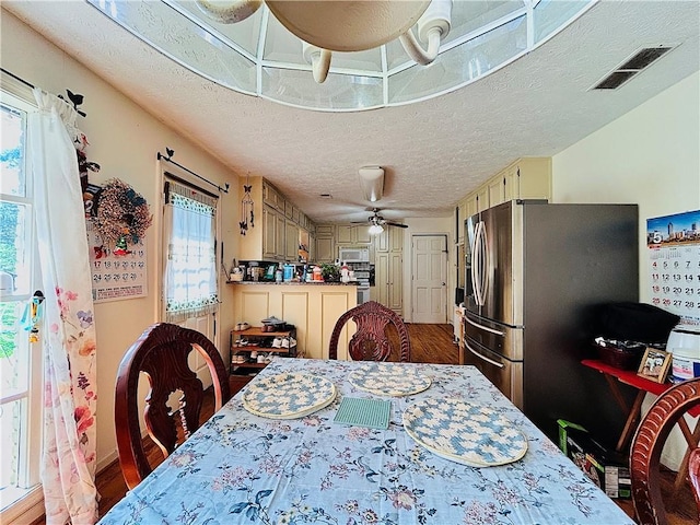 dining space with a textured ceiling, wood finished floors, and ceiling fan