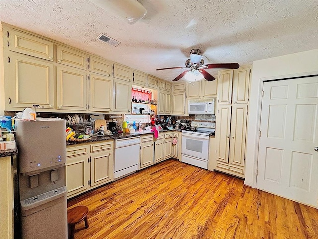 kitchen with white appliances, cream cabinets, a ceiling fan, dark countertops, and light wood-style flooring