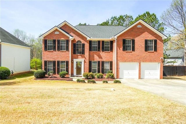 colonial house featuring fence, a front yard, brick siding, an attached garage, and driveway