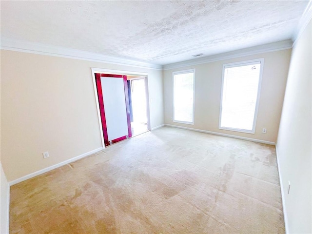 carpeted empty room with a textured ceiling, baseboards, and ornamental molding