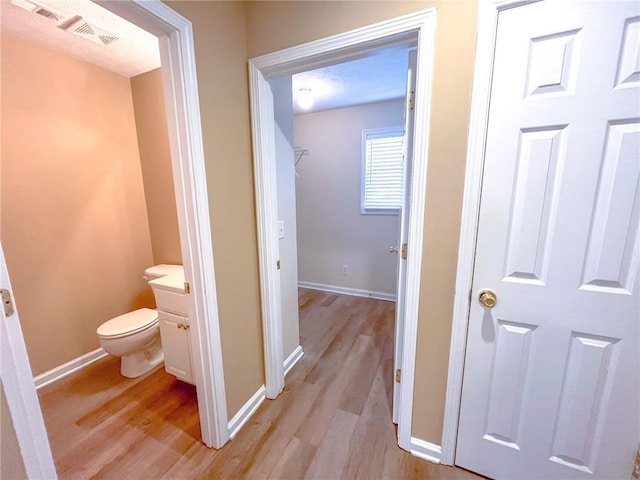 hallway with baseboards, visible vents, and light wood-style floors