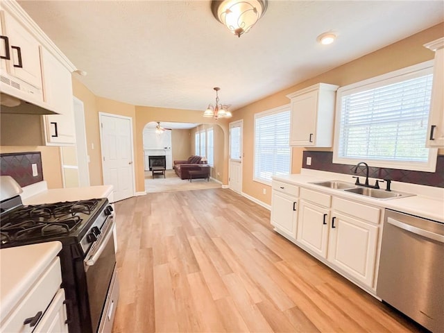 kitchen with appliances with stainless steel finishes, a sink, light wood-style floors, ceiling fan with notable chandelier, and white cabinetry