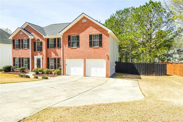 view of front facade featuring a front yard, a garage, brick siding, fence, and concrete driveway