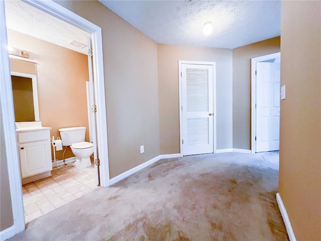 interior space featuring baseboards, light carpet, a closet, and a textured ceiling